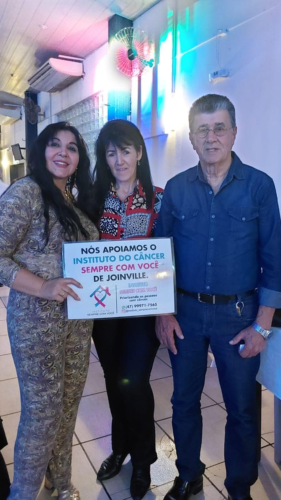 Cecília, voluntária e ex-paciente do Instituto, segurando placa de apoio à causa