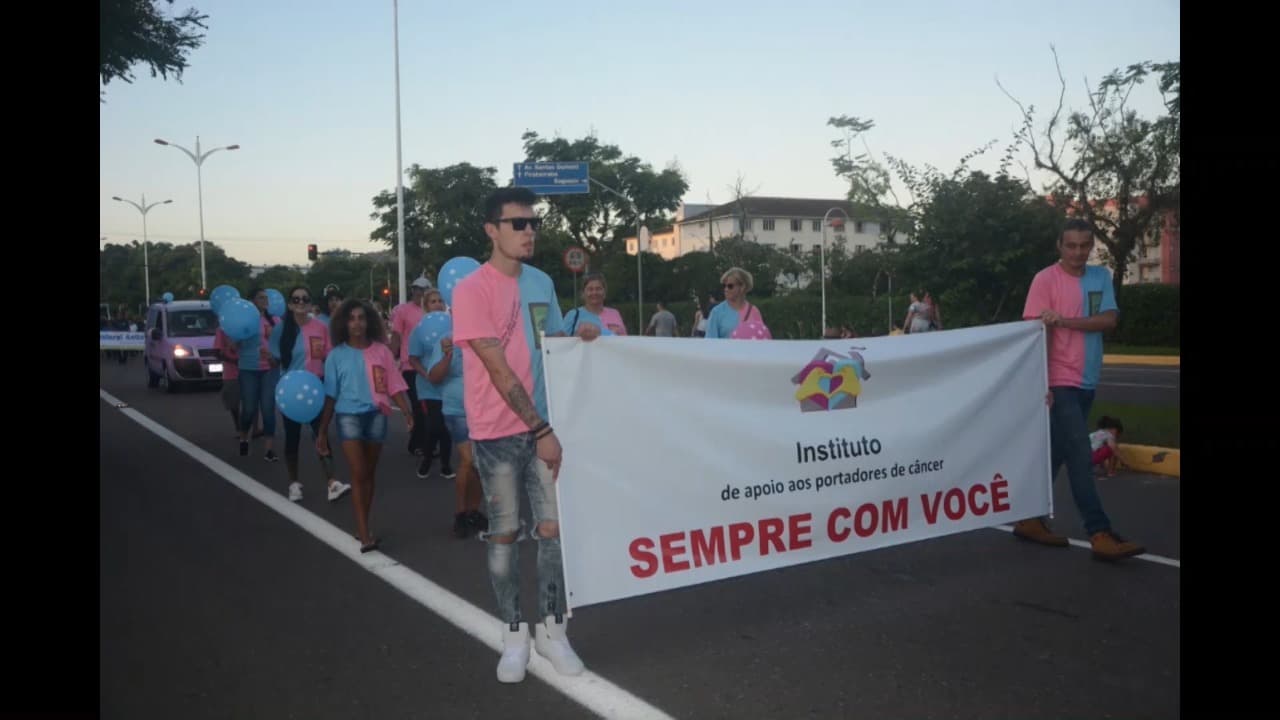 Instituto do Câncer Sempre Com Você desfilando com faixa e voluntários nas ruas de Joinville