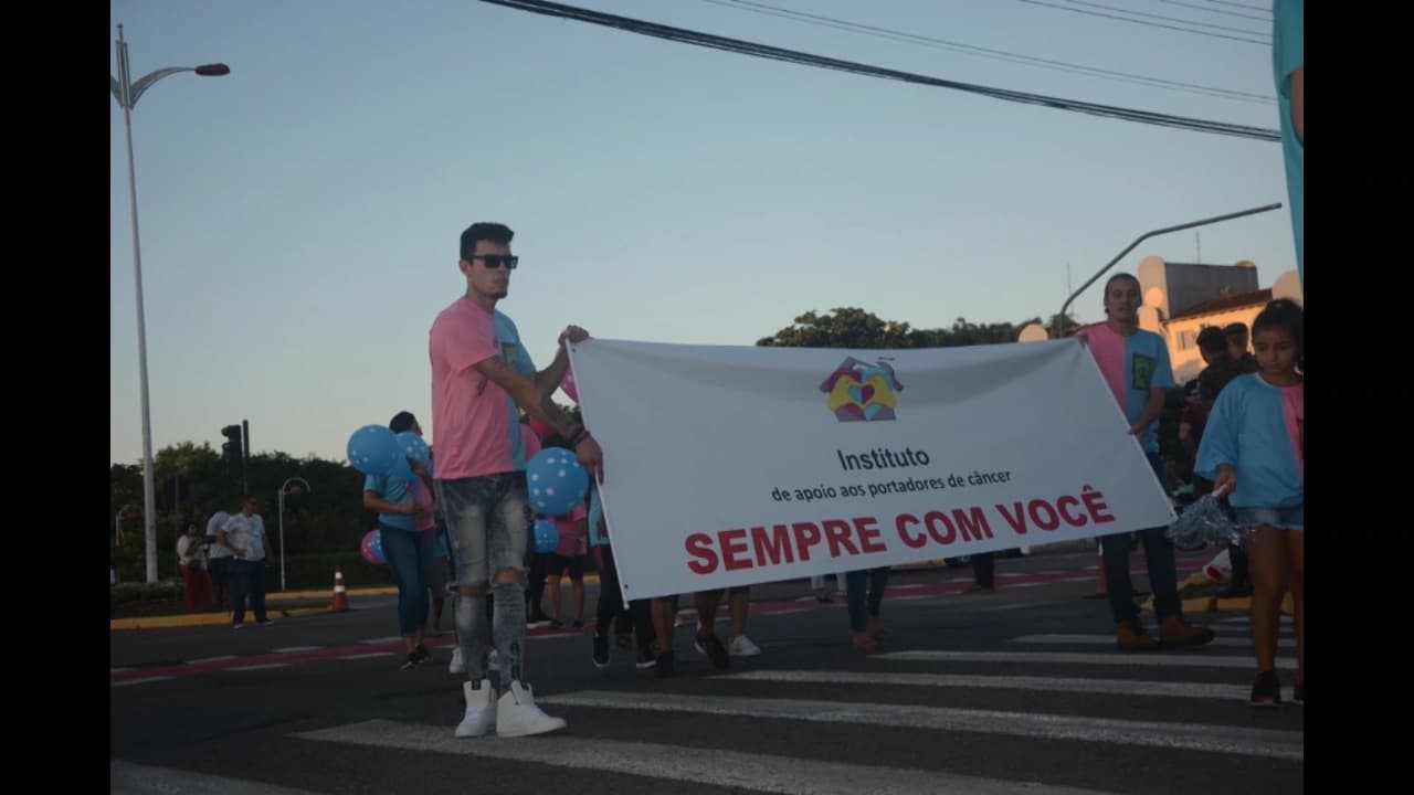 Grupo animado com balões rosa e azul no desfile de Joinville