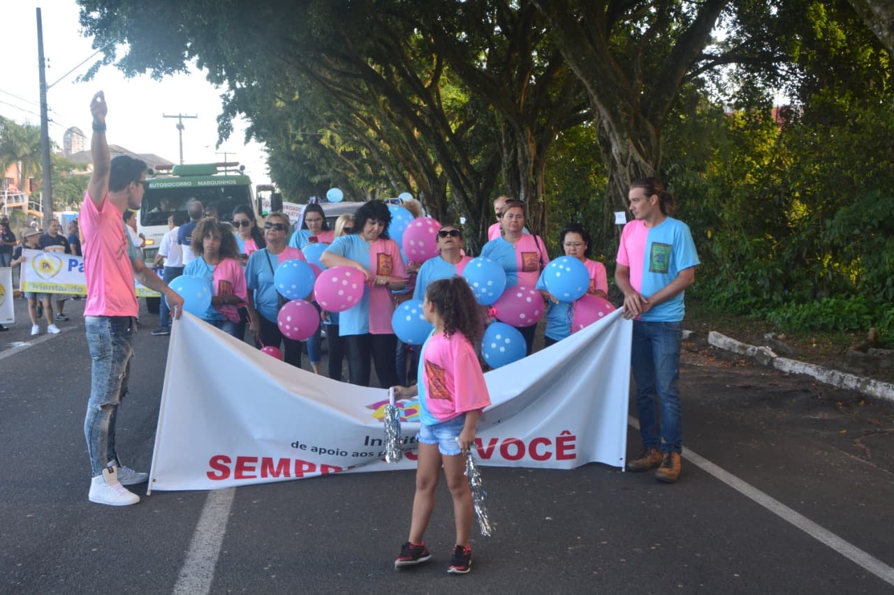Voluntários com balões coloridos ao longo do percurso do desfile